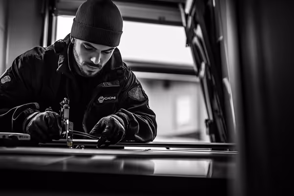 A garage door technician from Patterson in action, working carefully on realigning a track with modern tools at hand.